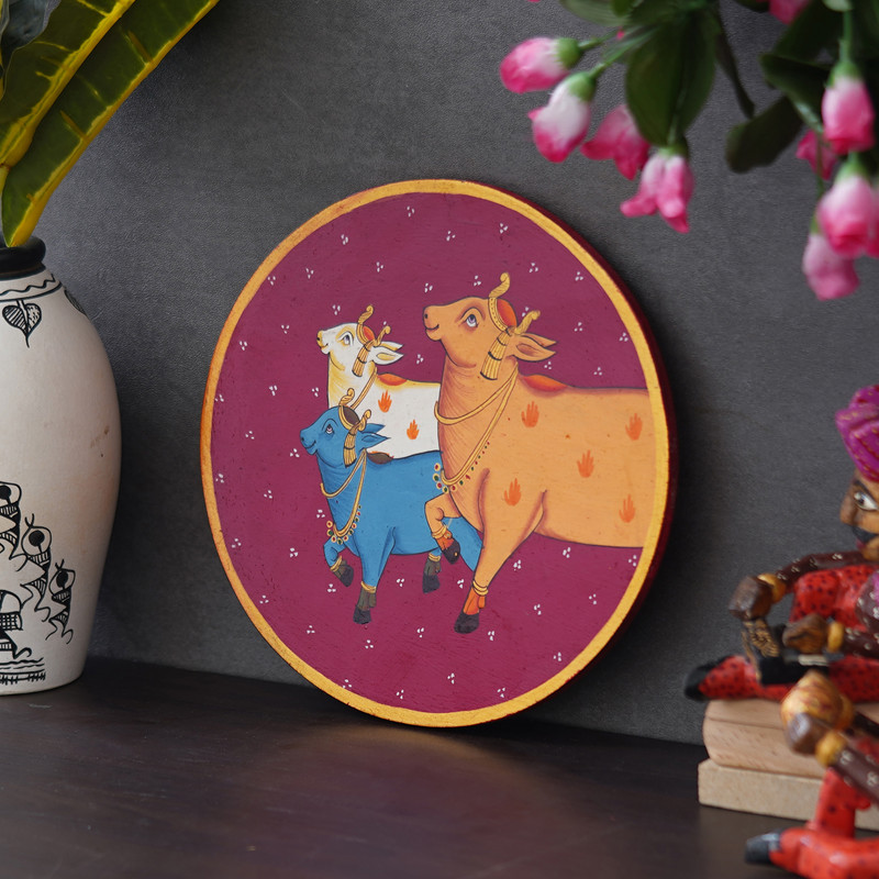 Hand-painted Pichwai cow trio on maroon background — vibrant Rajasthani artwork for ethnic home decor.