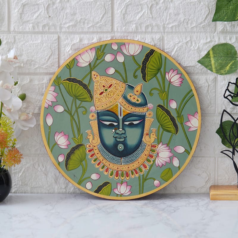 Artistic Pichwai painting depicting Shreenathji adorned with jewelry and lotus motifs — spiritual wall decor piece.