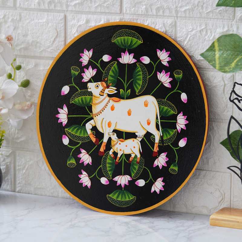 Elegant black background Pichwai painting of cow and calf with lotus flowers – traditional Indian wall art.