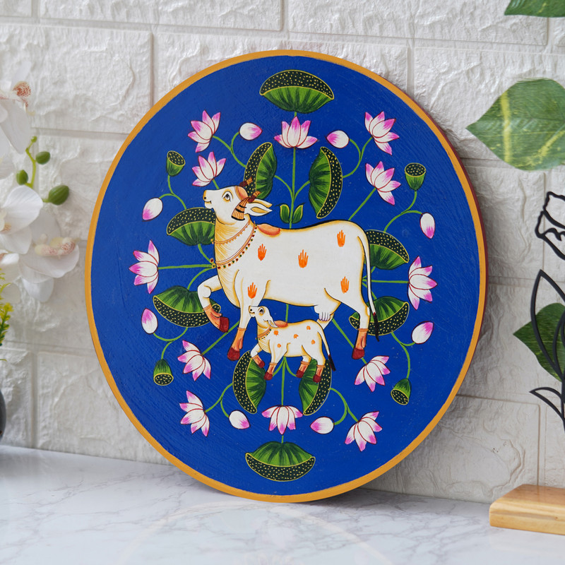 Traditional Pichwai cow and calf painting with lotus on blue background – spiritual Indian wall art decor.