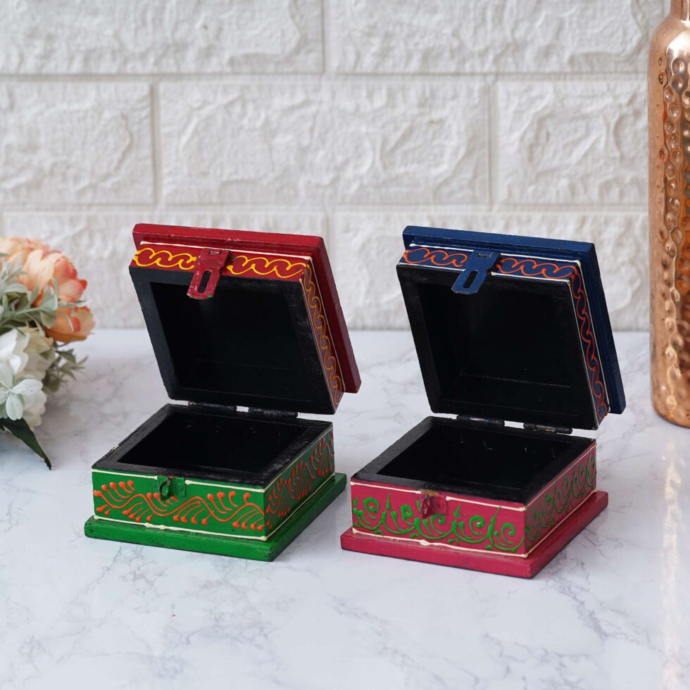 Handcrafted wooden storage boxes with intricate hand-painted designs in red and green.