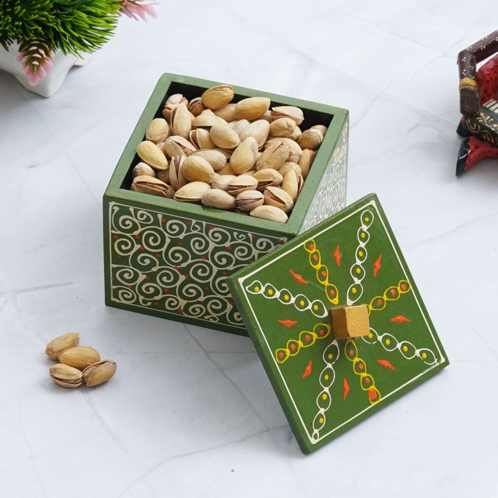 Ethnic hand-painted green wooden box filled with pistachios, ideal for kitchen decor and festive serving.